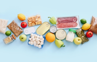 Verpakte voedingsmiddelen zoals brood, blikjes, vlees en fruit op een tafel