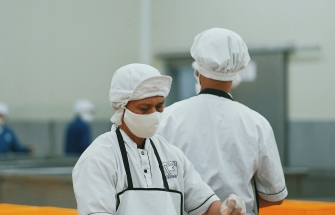 Chef in white uniform cutting meat in a professional food processing environment