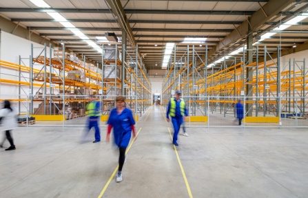 Des collaborateurs marchent dans une allée d'entrepôt d'un centre de stockage et de distribution