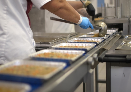Collaborateur remplissant des barquettes alimentaires sur une ligne de production